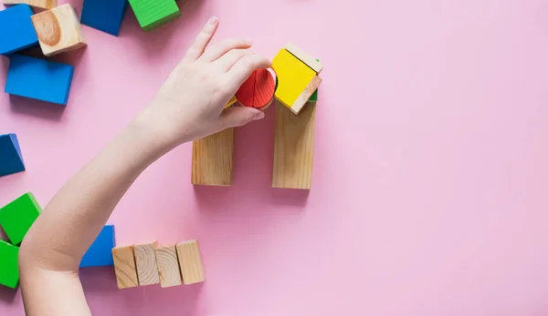 A criança reúne o desenhista constrói uma casa de cubos de madeira. Brinquedos de materiais naturais ambientais para crianças . — Fotografia de Stock