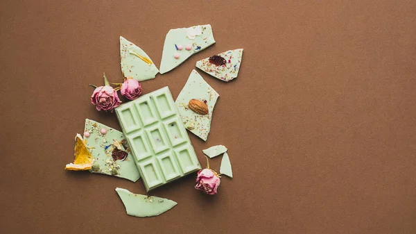 Chocolate bar whole with the addition of pistachios brown background. Top view flat layout. Horizontal frame copy space