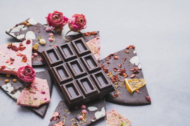 Meyve fıstığı ve dilimlenmiş gri arka planla süslenmiş koyu sütlü çikolata. Minimalizm tek renklidir..