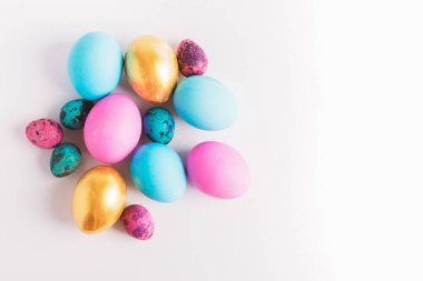 Mutlu Paskalyalar. Değişik renklerde büyük küçük yumurtalar beyaz arka planda bir yığın halinde yatar. Boşluğu kopyala