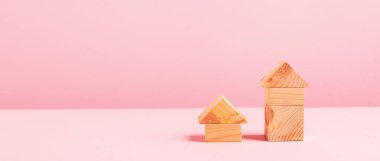 Pembe arka planda büyük ve küçük tahta küplü evler. Çevre dostu evler inşa etme kavramı