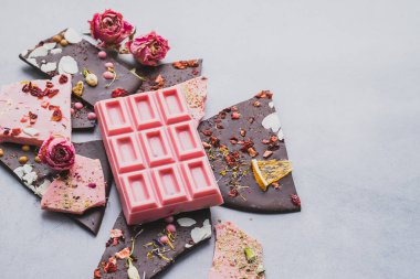 Chocolate pink whole bar decorated with slices of fruits nuts and slices gray background. Minimization