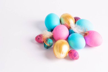 Mutlu Paskalyalar. Değişik renklerde büyük küçük yumurtalar beyaz arka planda bir yığın halinde yatar. Boşluğu kopyala