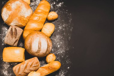 Altın kabuklu taze ekmek çeşitleri ve siyah bir kırsal arka plan. Reklam için yeri olan düz bir düzen.