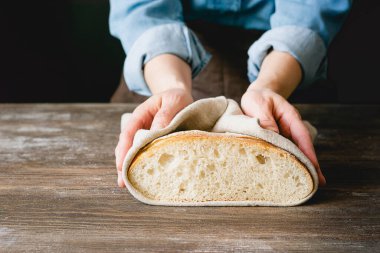 Kadın elinde bir somun taze dilimlenmiş ekmek tutuyor koyu bir arka plan. Kırsal ev fırını tarzı. Yatay çerçeve