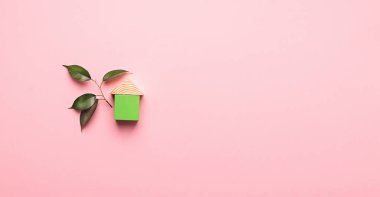 Pembe arka planda tahta küplerden yapılmış bir ev. Çevre dostu malzemelerden ev inşa etme kavramı.