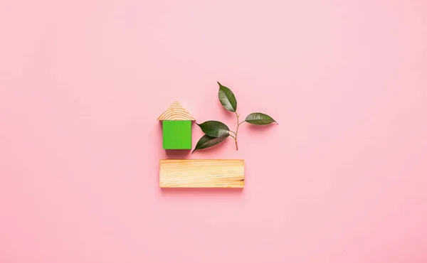 분홍색 배경에 나무로 만든 집입니다. 환경 친화적 인 재료로 집을 짓는다는 개념. — 스톡 사진
