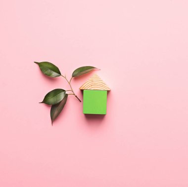 Pembe arka planda tahta küplerden yapılmış bir ev. Çevre dostu malzemelerden ev inşa etme kavramı.