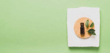 Aromaterapi şişesi taze çay ağacı yağı kozmetik spa tedavileri için yumuşak beyaz havlu pastel yeşil nane arkaplan .