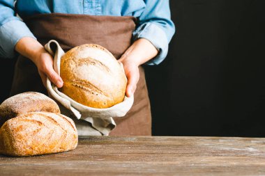 Kadın elinde bir somun taze dilimlenmiş ekmek taşralı arka planını tutuyor. Ev yapımı diyet pişirme konsepti