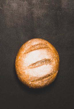 Koyu arkaplanda altın kabuklu taze pişmiş ekmek. Minimalizm gıda konsepti. Dikey çerçeve kopyalama alanı
