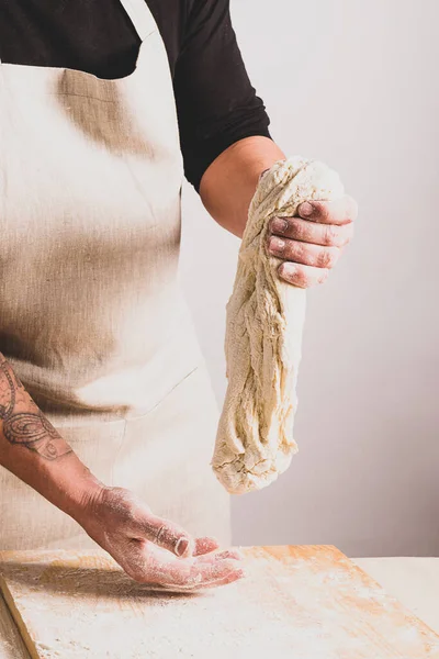 효모가 없는 가정용 빵을 만드는 콘셉트 과정. 한 사람 이 남비에 반죽을 넣고 반죽을 하여 식탁에 얹는다. — 스톡 사진