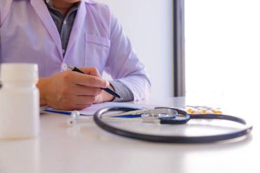 Doktor masaya oturdu, çalıştı, hastanın belgelerini kontrol etti.