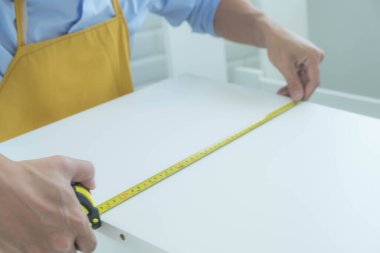 Tamirci mobilyaları el kitabına göre ve mekanik ekipmanlarla birlikte evde monte etti. Çivileri çekiçle çakarak mezura ile ölçerek vida delme deliklerini vidalayarak.