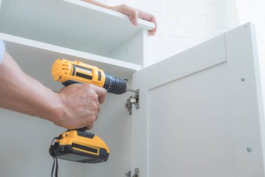 Tamirci mobilyaları el kitabına göre ve mekanik ekipmanlarla birlikte evde monte etti. Çivileri çekiçle çakarak mezura ile ölçerek vida delme deliklerini vidalayarak.