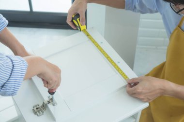 Tamirci mobilyaları el kitabına göre ve mekanik ekipmanlarla birlikte evde monte etti. Çivileri çekiçle çakarak mezura ile ölçerek vida delme deliklerini vidalayarak.