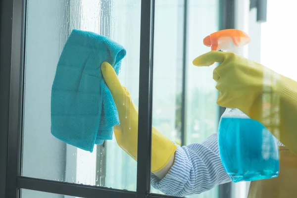 The cleaning staff uses a cloth and dust brush on the window surface with blinds and uses cleaning agents to kill germs and viruses.