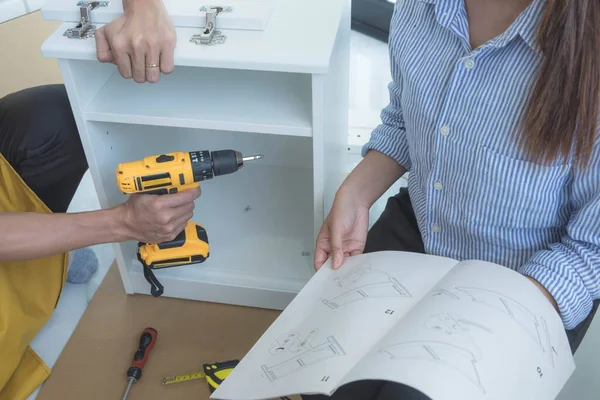 The mechanic assembled the furniture in the house according to the manual, along with the mechanic equipment. By hammering the nails Measuring with a tape measure Screwing the screw Drilling holes.