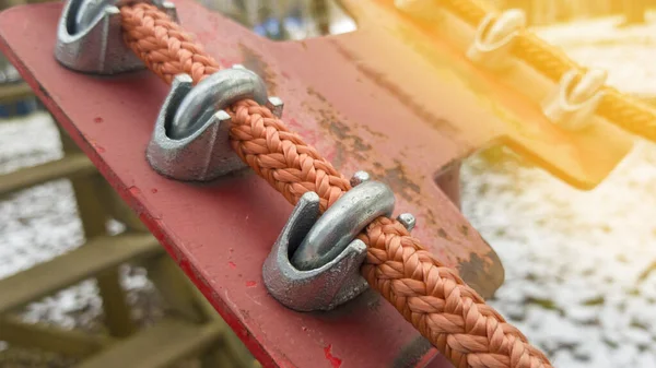 Close up of red rope and metal clips used for suspension bridge to the ...