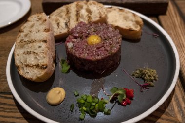 Koyu mermer arka plan yakın çekim üzerinde salatalık turşusu ve taze soğan ile Sığır tartar