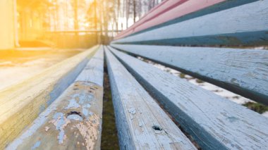 Yeşil çimenlerin ve beyaz karın arka planında çok renkli tahtalardan oluşan sokak bankı