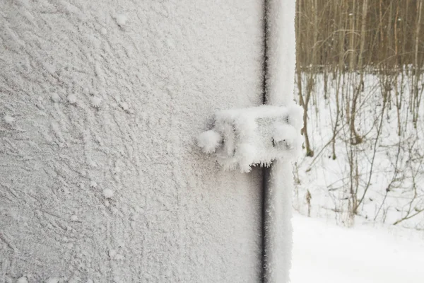 Porta de metal e maçaneta da porta e fechadura são cobertos com geada. geadas severas. A porta congela. punho gelado e bloqueio coberto com flocos de neve . Imagem De Stock