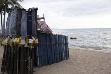 Kapalı bir şemsiye ve kumsalda katlanır bir plaj sandalyesi.