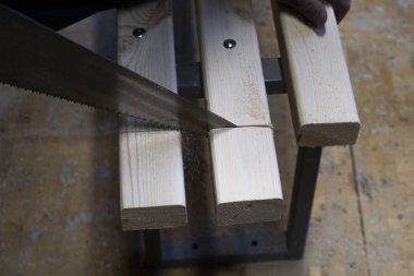 Testereyle kesmek veya marangozluk veya marangozluk çalışmaları sırasında bir inşaat alanında bir ahşap tahta veya çubuk bir el testeresi veya demir testeresi ile kesme.