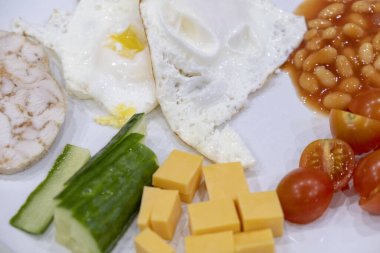 Morning Breakfast of eggs, chicken, cheese, cucumbers, tomatoes on a plate close-up