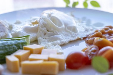 Morning Breakfast of eggs, chicken, cheese, cucumbers, tomatoes on a plate close-up