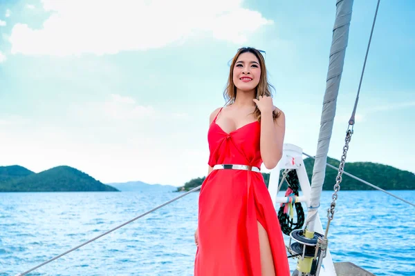 在白天乘船旅行时 穿着红色衣服的漂亮亚洲女人站在游艇的船头上 — 图库照片