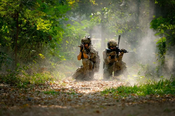 两名身穿战斗服的士兵坐在地上 用枪指向目标 准备在丛林中进行概念性的战争 — 图库照片