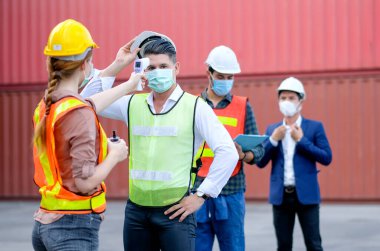 Teknisyen ya da mühendis, nakliye konteynır işyerindeki diğer personelin kızılötesi termometre ölçüm sıcaklığını kullanır ve dünyanın dört bir yanındaki covid salgın sırasında aynı hizada kalırlar..