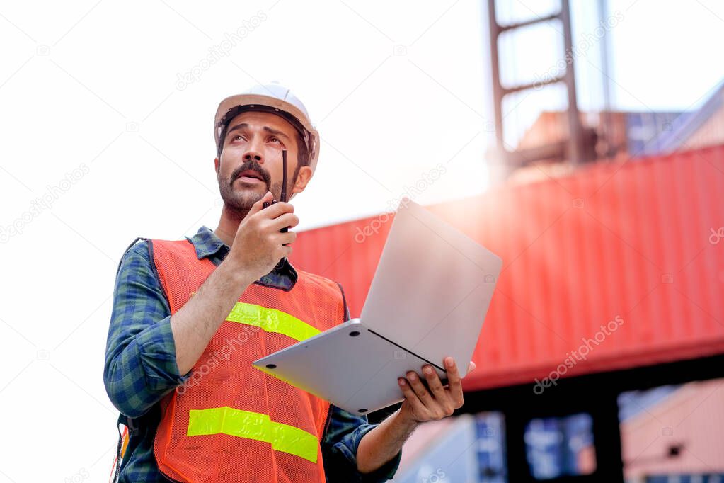 Technician or engineer worker with laptop use walkie talkie to contact with his manager in cargo shipping workplace area. Concept with good communication system help to improve better industrial.