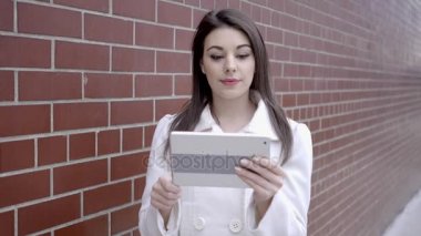 sokakta duran ve tablet bilgisayarı kullanan kadın