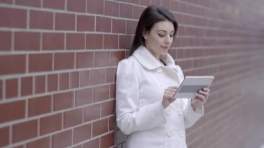 sokakta duran ve tablet bilgisayarı kullanan kadın