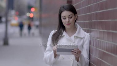 sokakta duran ve tablet bilgisayarı kullanan kadın