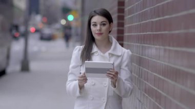 sokakta duran ve tablet bilgisayarı kullanan kadın