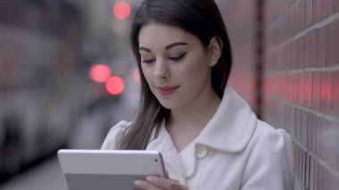 sokakta duran ve tablet bilgisayarı kullanan kadın