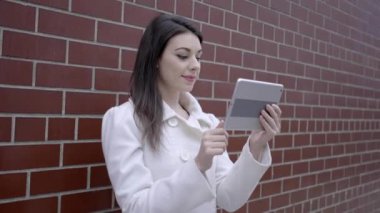 sokakta duran ve tablet bilgisayarı kullanan kadın