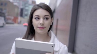 sokakta duran ve tablet bilgisayarı kullanan kadın