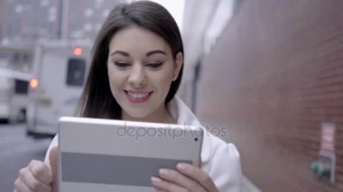 sokakta duran ve tablet bilgisayarı kullanan kadın