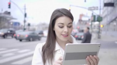 sokakta duran ve tablet bilgisayarı kullanan kadın