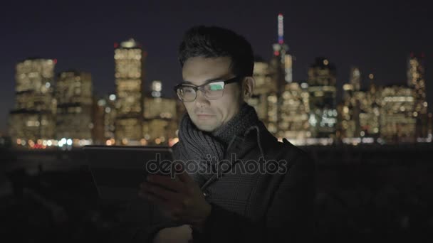 Азіатський чоловік використовує планшетний комп'ютер вночі — стокове відео