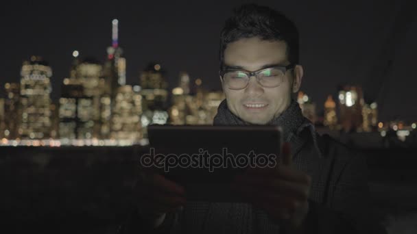 Азиатский человек, использующий планшетный компьютер ночью — стоковое видео