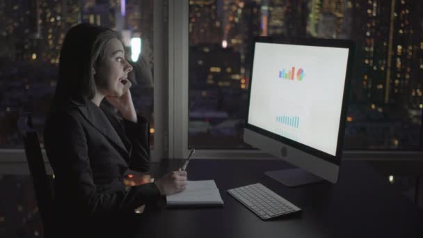 Affärskvinna arbetar med dator och pratar i mobiltelefon — Stockvideo