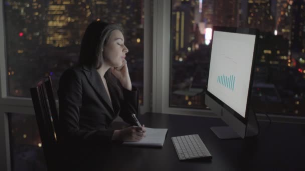 Mujer de negocios trabajando en la computadora y hablando en el teléfono móvil — Vídeo de stock