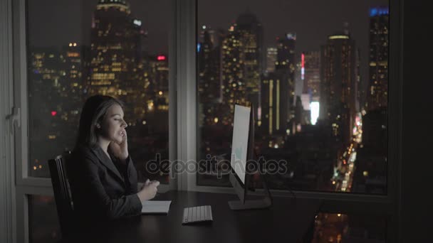 Mujer de negocios trabajando en la computadora y hablando en el teléfono móvil — Vídeo de stock