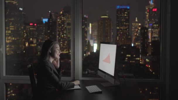 Mujer de negocios trabajando en la computadora y hablando en el teléfono móvil — Vídeos de Stock