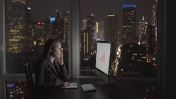 Mujer de negocios trabajando en la computadora y hablando en el teléfono móvil — Vídeo de stock